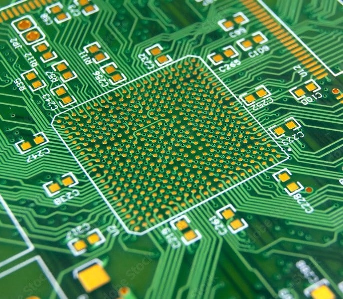 Close-up of a green printed circuit board with a micro BGA pad array in the center.