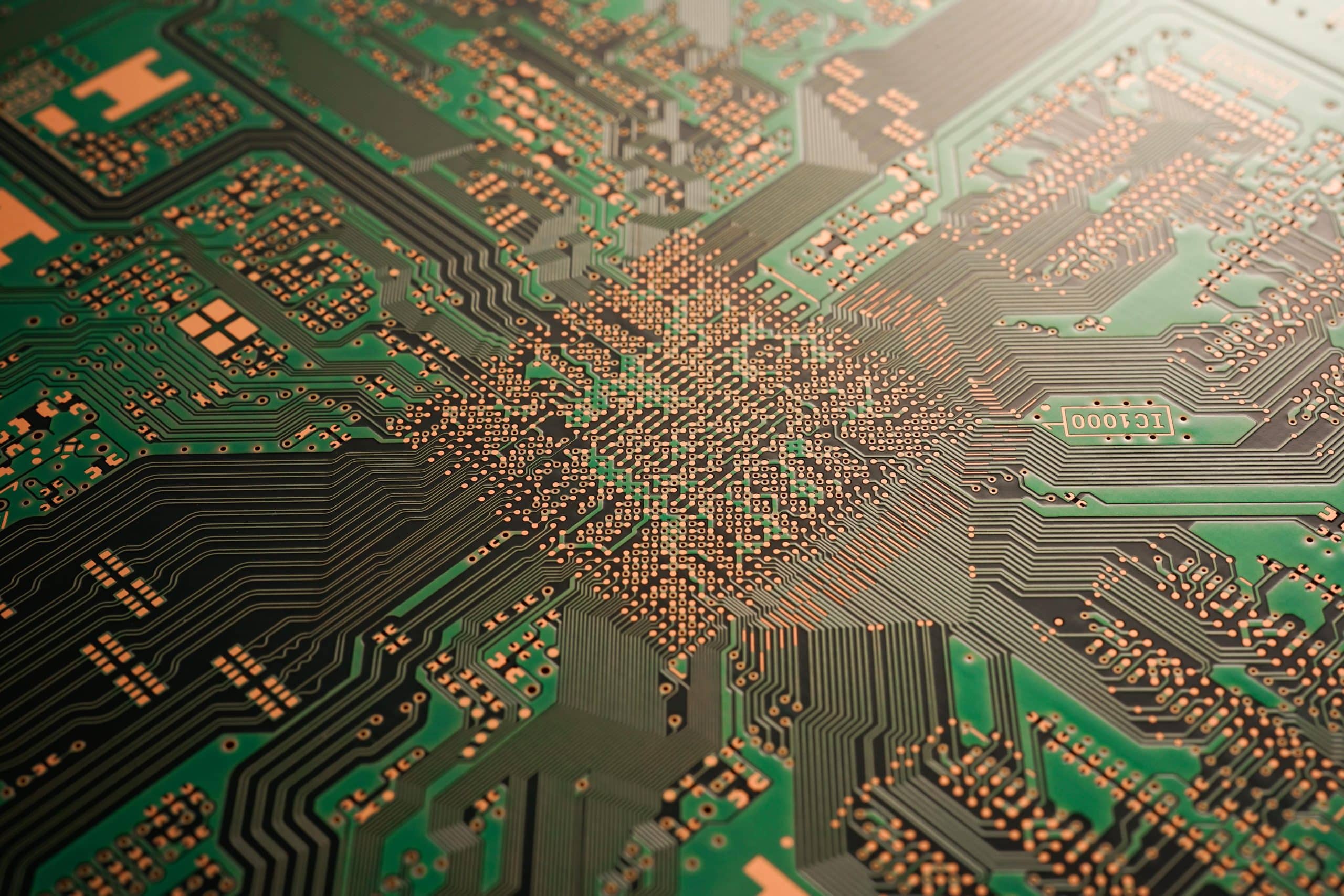 Close-up of a green printed circuit board with intricate copper pathways and connection points.